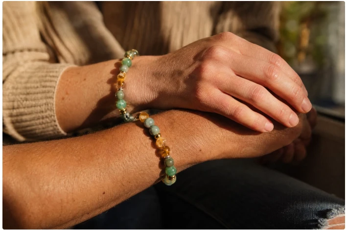 Deux bracelets aux trois pierres portés sur des poignets croisés